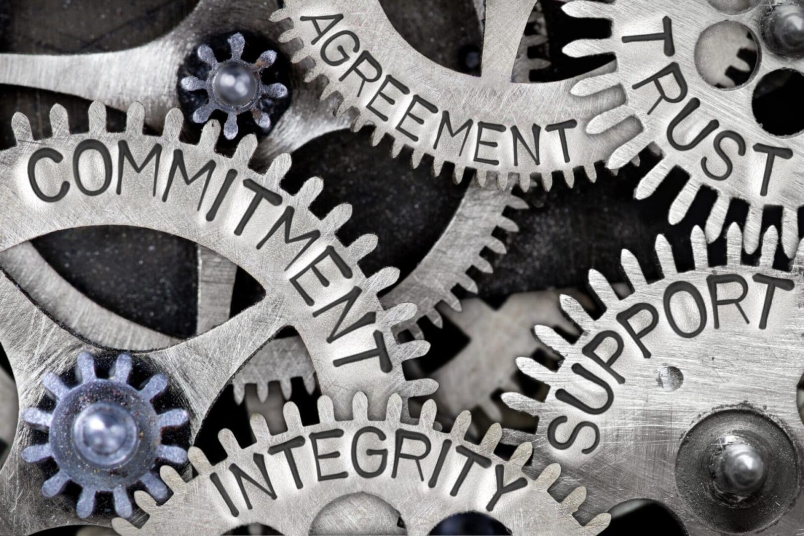 A close up of some gears with the words " agreement ," " commitment ", and " integrity."