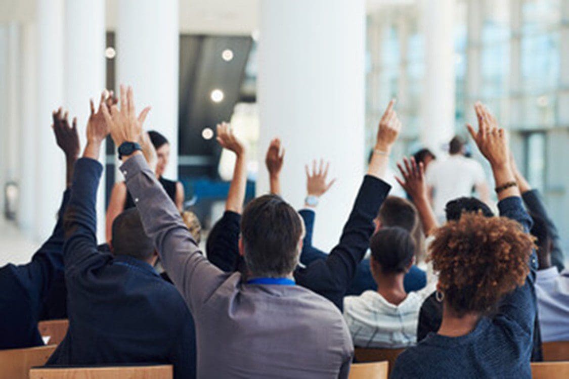 A group of people raising their hands in the air.