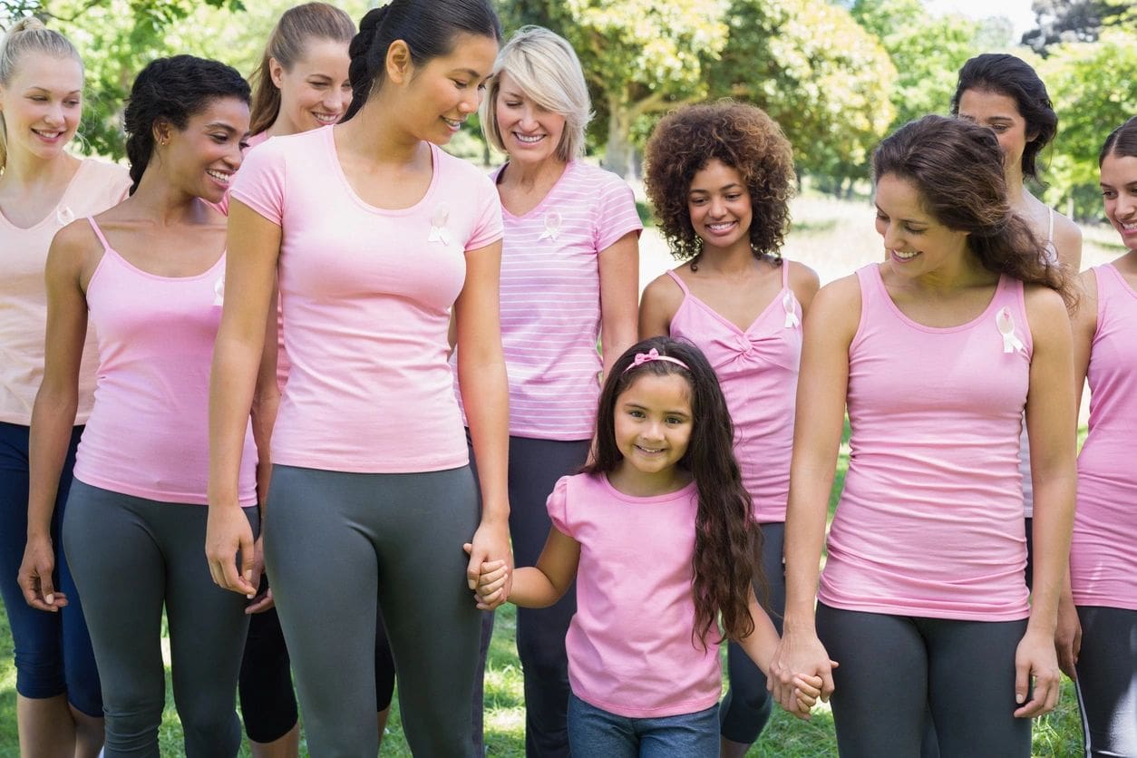 A group of women in pink shirts holding hands.